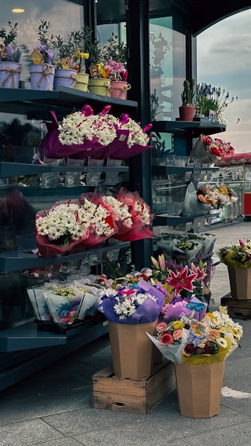 An indoor display of various floral arrangements and bouquets showcasing fresh flowers in vibrant colors such as white, pink, purple, and yellow. These arrangements include chrysanthemums, lilies, and